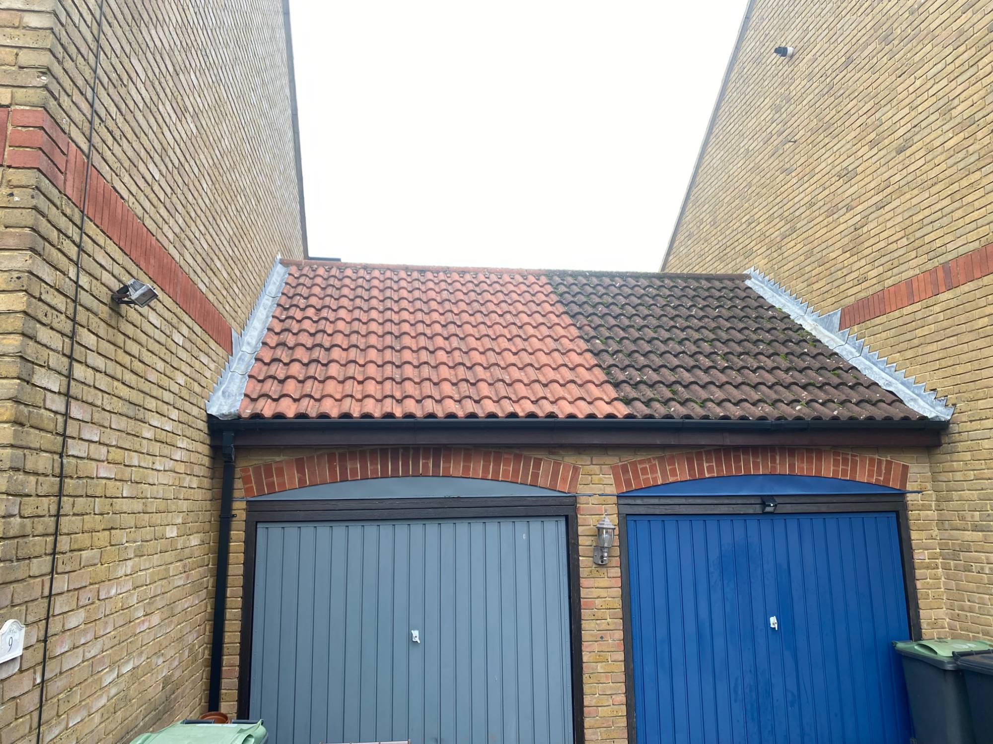 Real customer roof mid-job — left side scraped and biocide-treated, right side still moss-covered before starting
